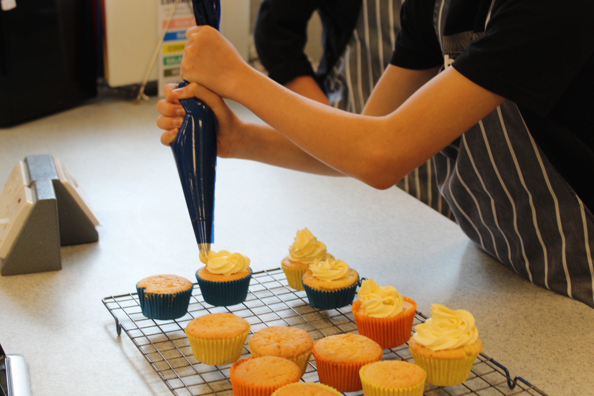 Student piping decoration onto a cupcake